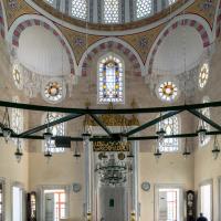 Cerrah Mehmed Pasha Camii - Interior: Southeast Qibla Wall, Mihrab, Quranic Inscription, Calligraphic Medallions, Light Fixtures, Muqarnas, Stained Glass Windows
