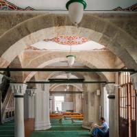 Cerrah Mehmed Pasha Camii - Interior: Southwest Side Aisle, Facing Southeast, Muqarnas Column Capitals, Light Fixtures, Southwest Auxiliary Mosque Entrance